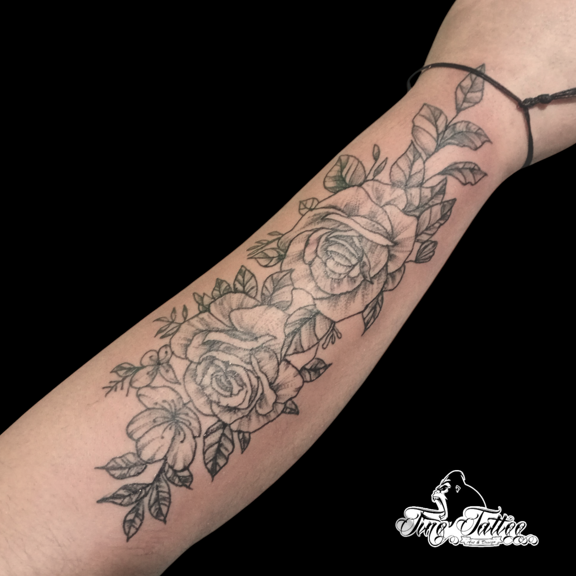 Tatuaje fineline de rosas y hojas en composición vertical sobre el antebrazo