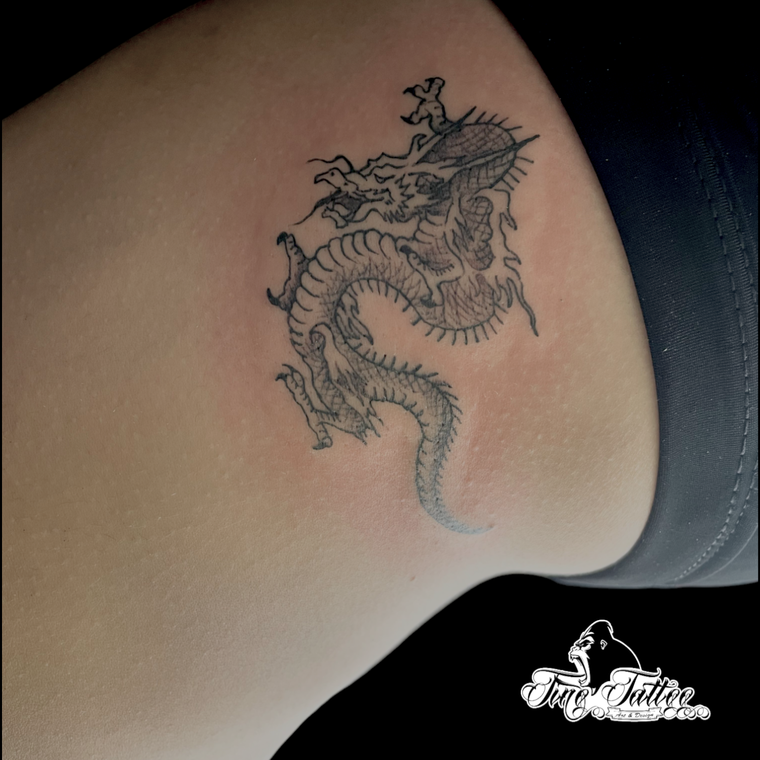 Tatuaje pequeño de dragón oriental en tinta negra sobre la cadera