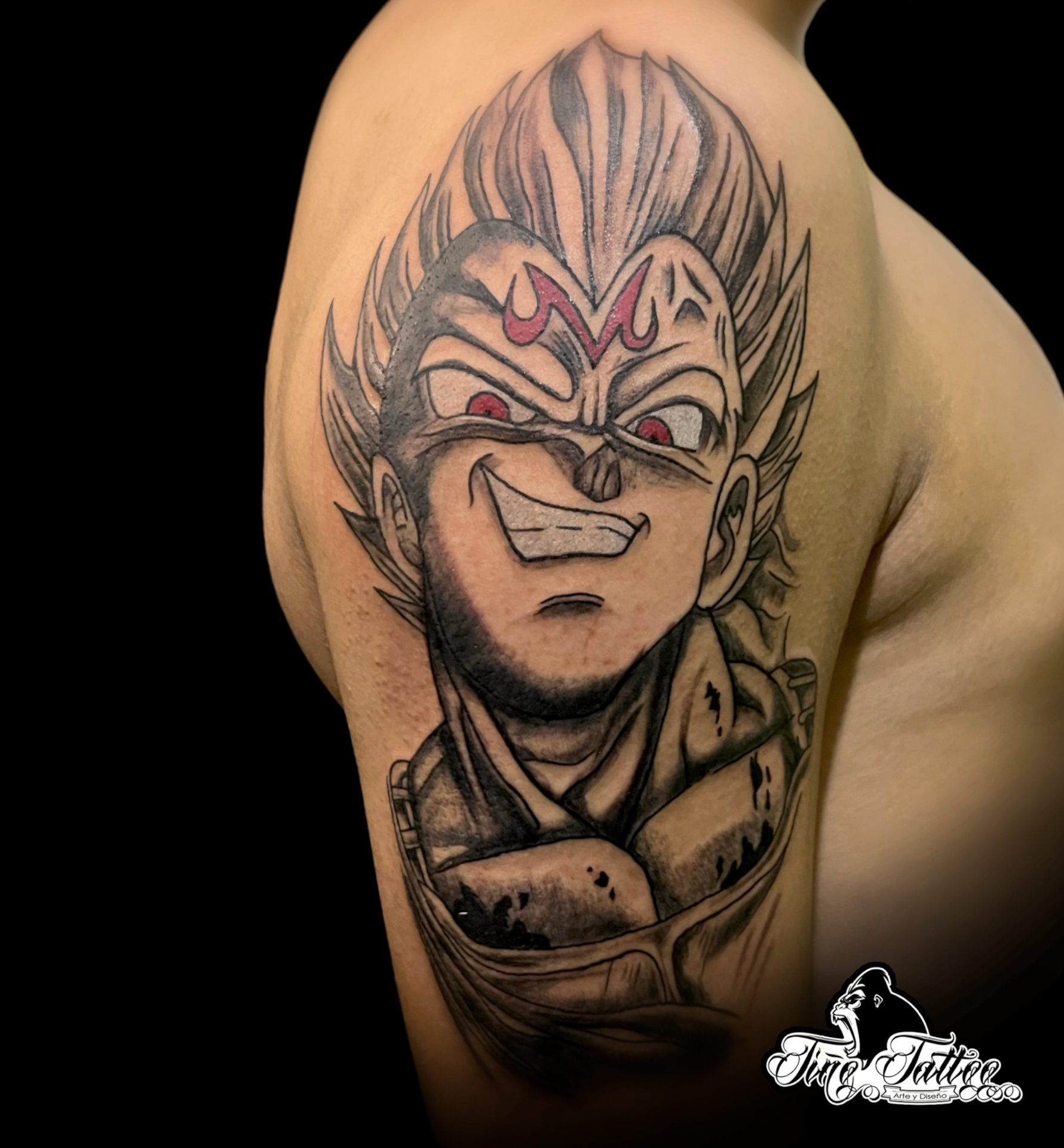 Tatuaje estilo anime de Vegeta Majin en negro y gris con acentos rojos en el hombro