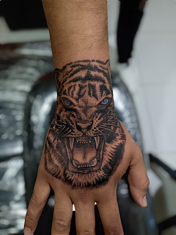 Tatuaje blackwork de tigre rugiendo sobre la mano