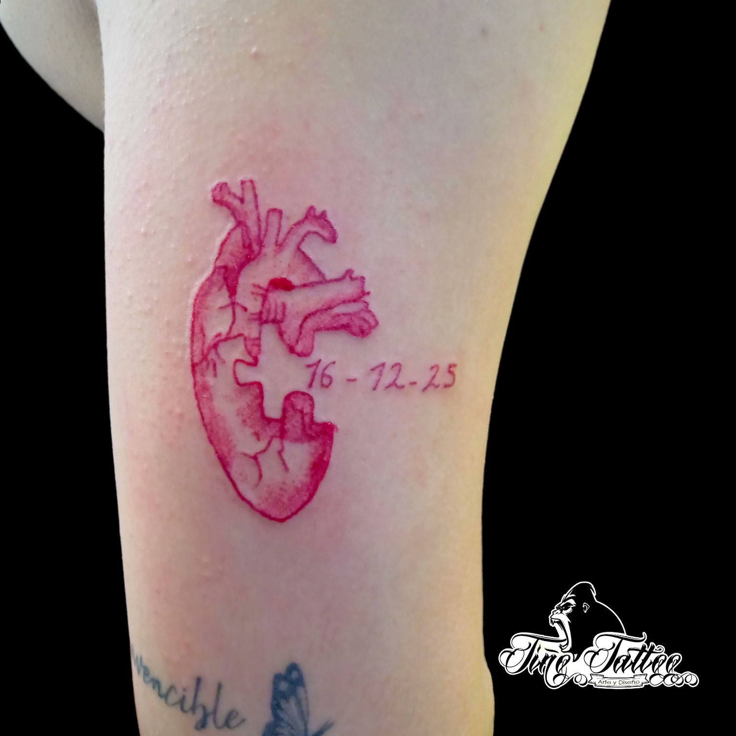 Tatuaje en tinta roja de corazón anatómico con fecha y pieza de rompecabezas