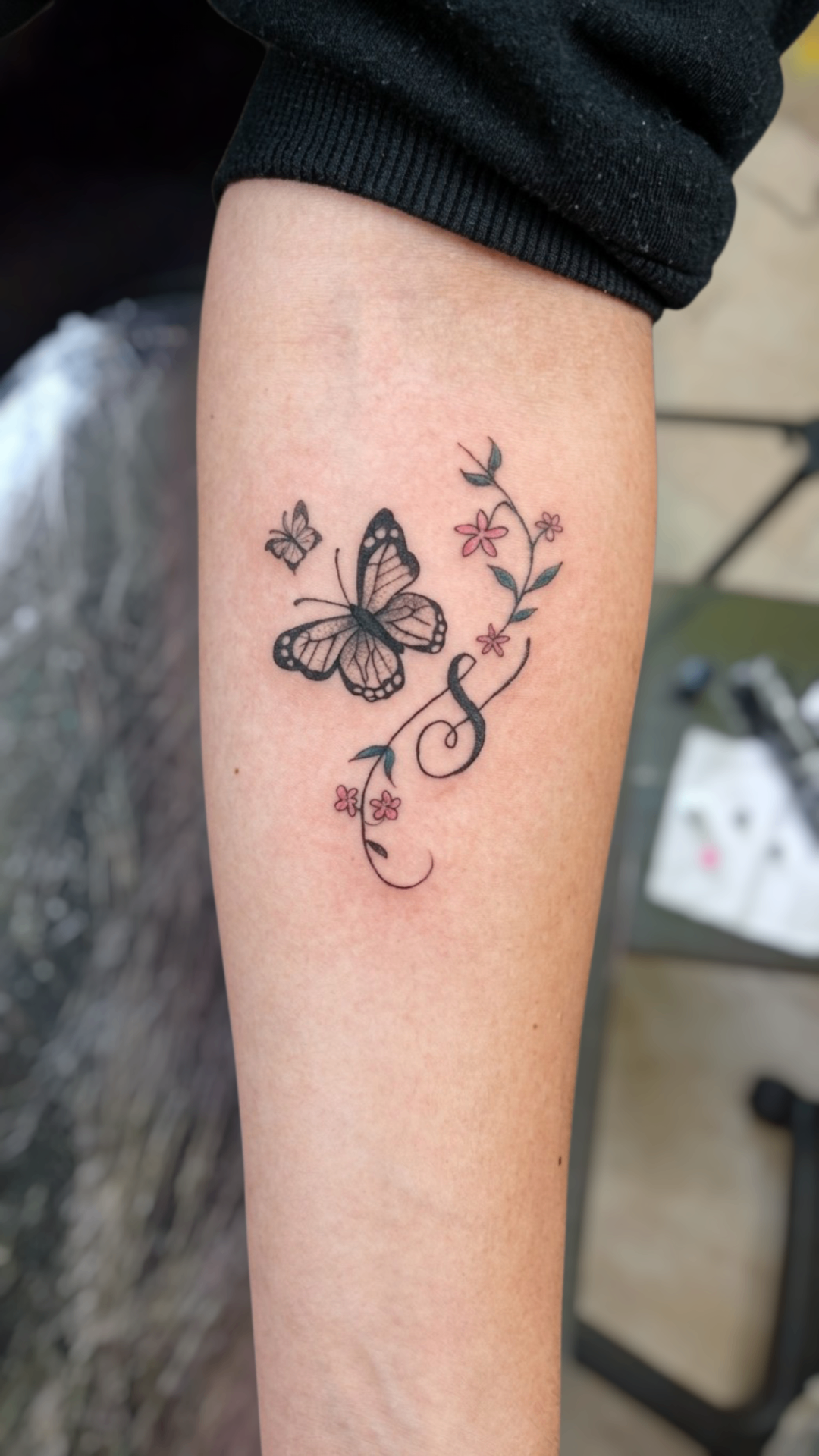 Tatuaje de mariposa con clave musical y flores