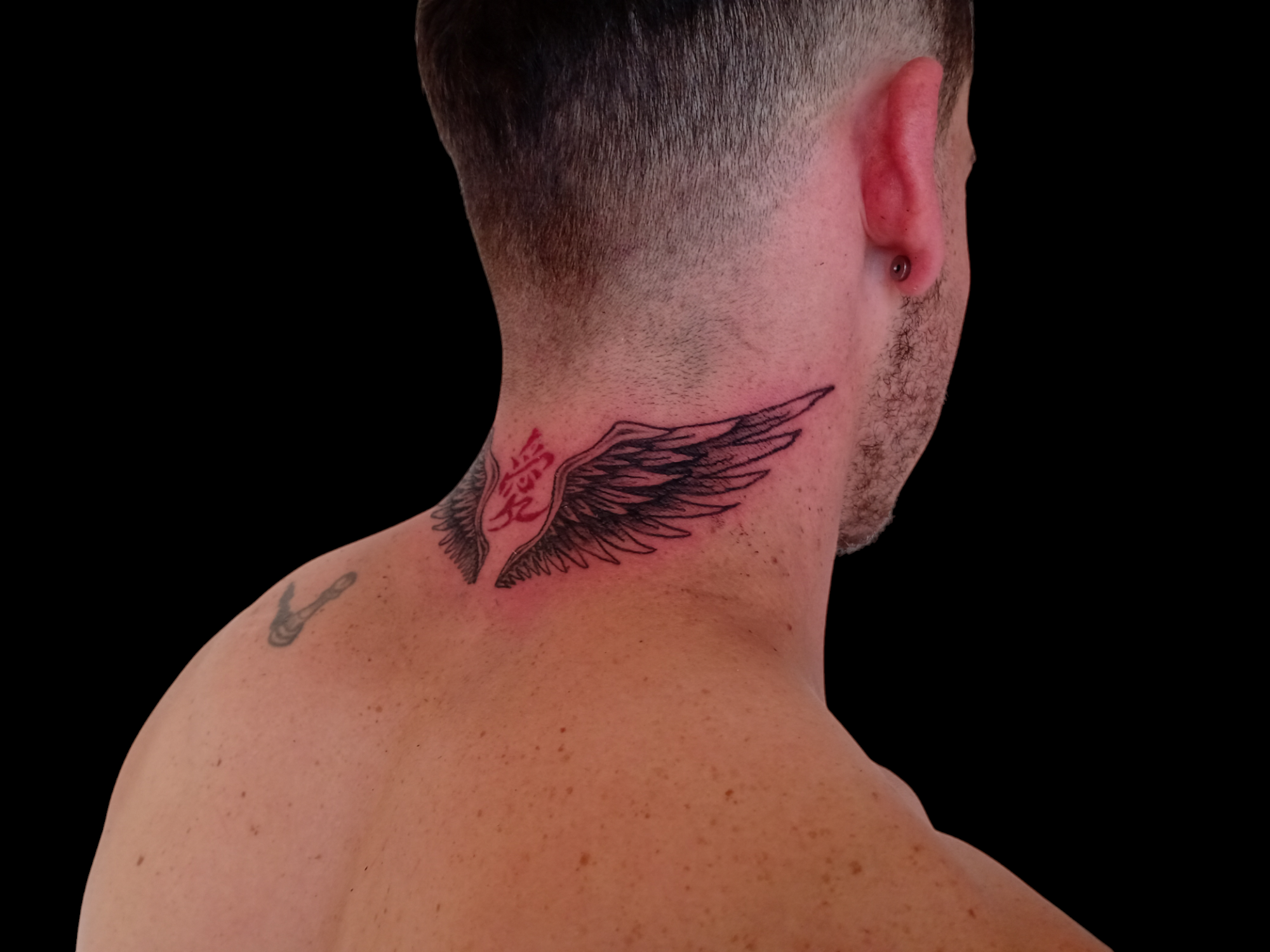 Tatuaje fineline de ala con símbolo rojo en la parte posterior del cuello