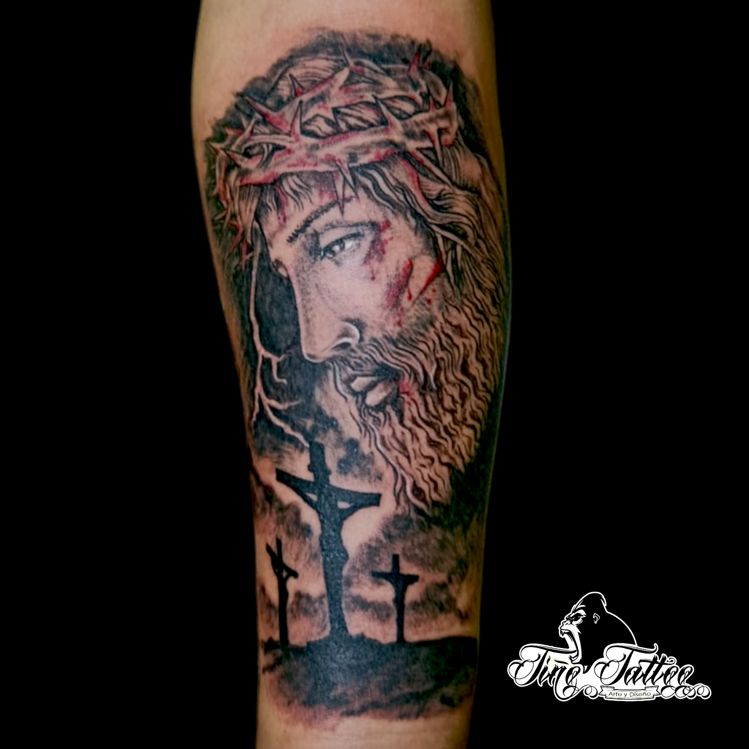 Tatuaje blackwork de rostro de Cristo con corona de espinas y siluetas de cruces