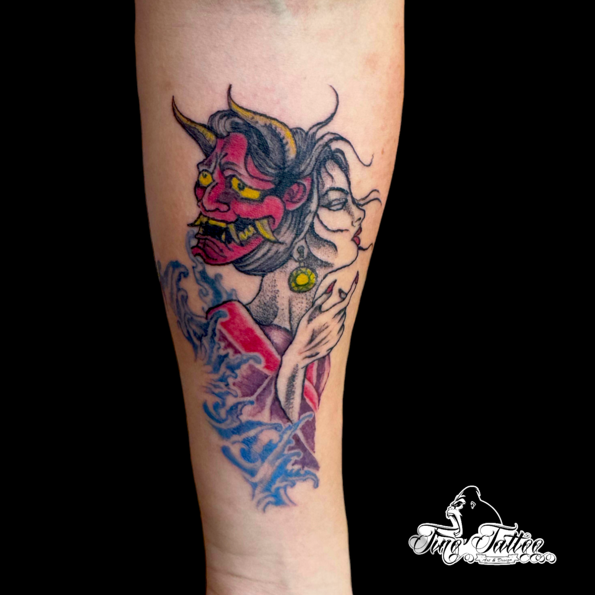 Tatuaje a color de máscara Hannya junto a rostro femenino y olas azules